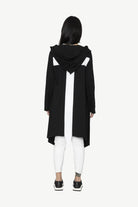 black longline jacket over white outfit worn by model cross back