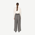 model wearing white top and grey wide leg pants on white background back angle