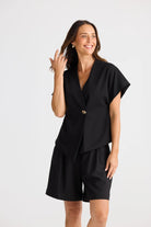 Model wearing black structural top and black shorts on white background