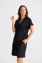 Model wearing black structural top and black shorts on white background