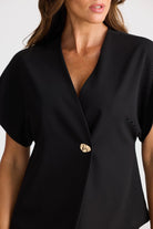 Black blazer with a gold button worn by a person on a white background