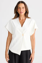 Woman wearing a white blouse with a V-neck and short sleeves on a plain background