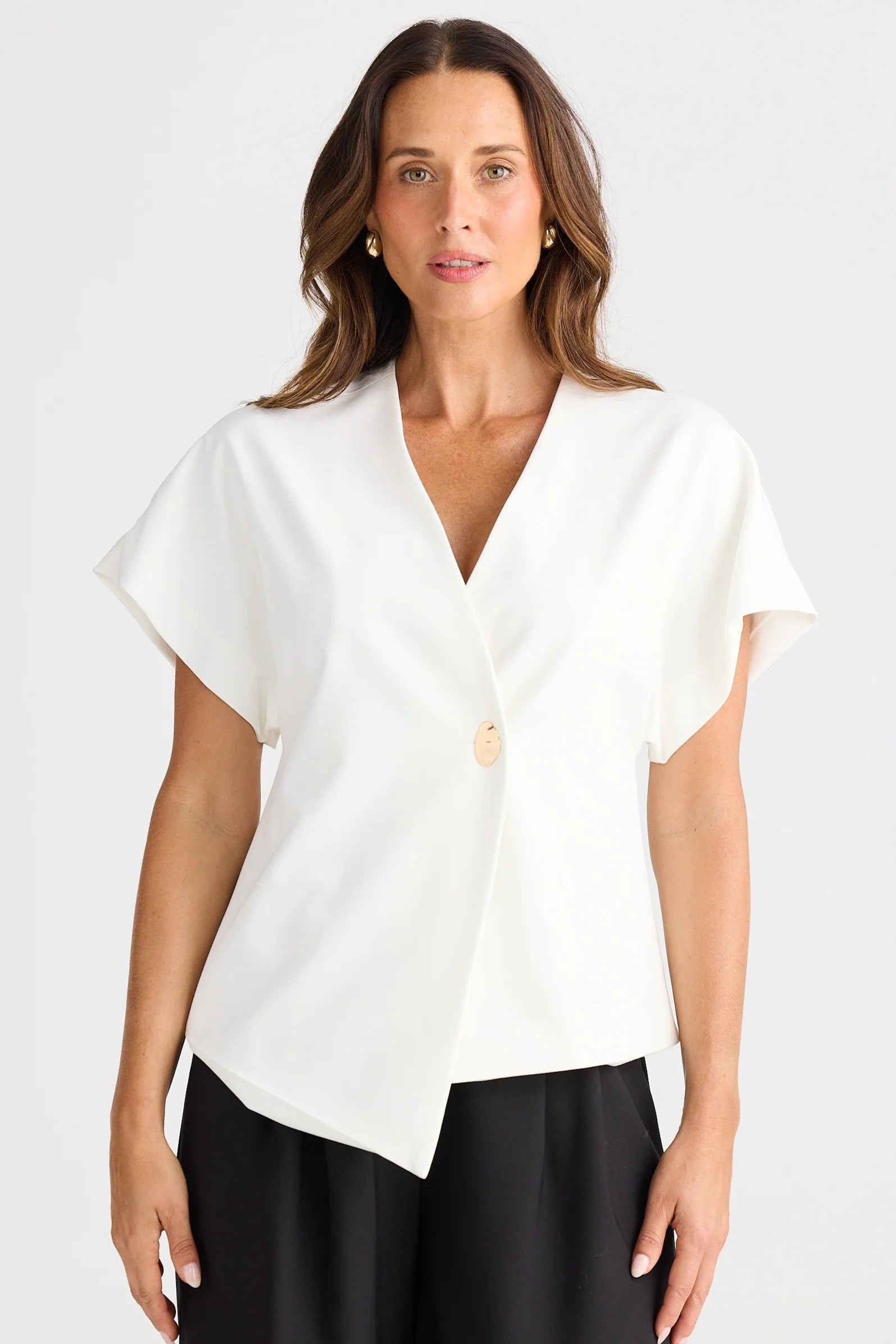 Woman wearing a white blouse with a V-neck and short sleeves on a plain background