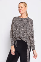 Woman wearing a black and white patterned blouse with black pants on a white background