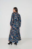 Woman wearing a long, patterned dress against a white background