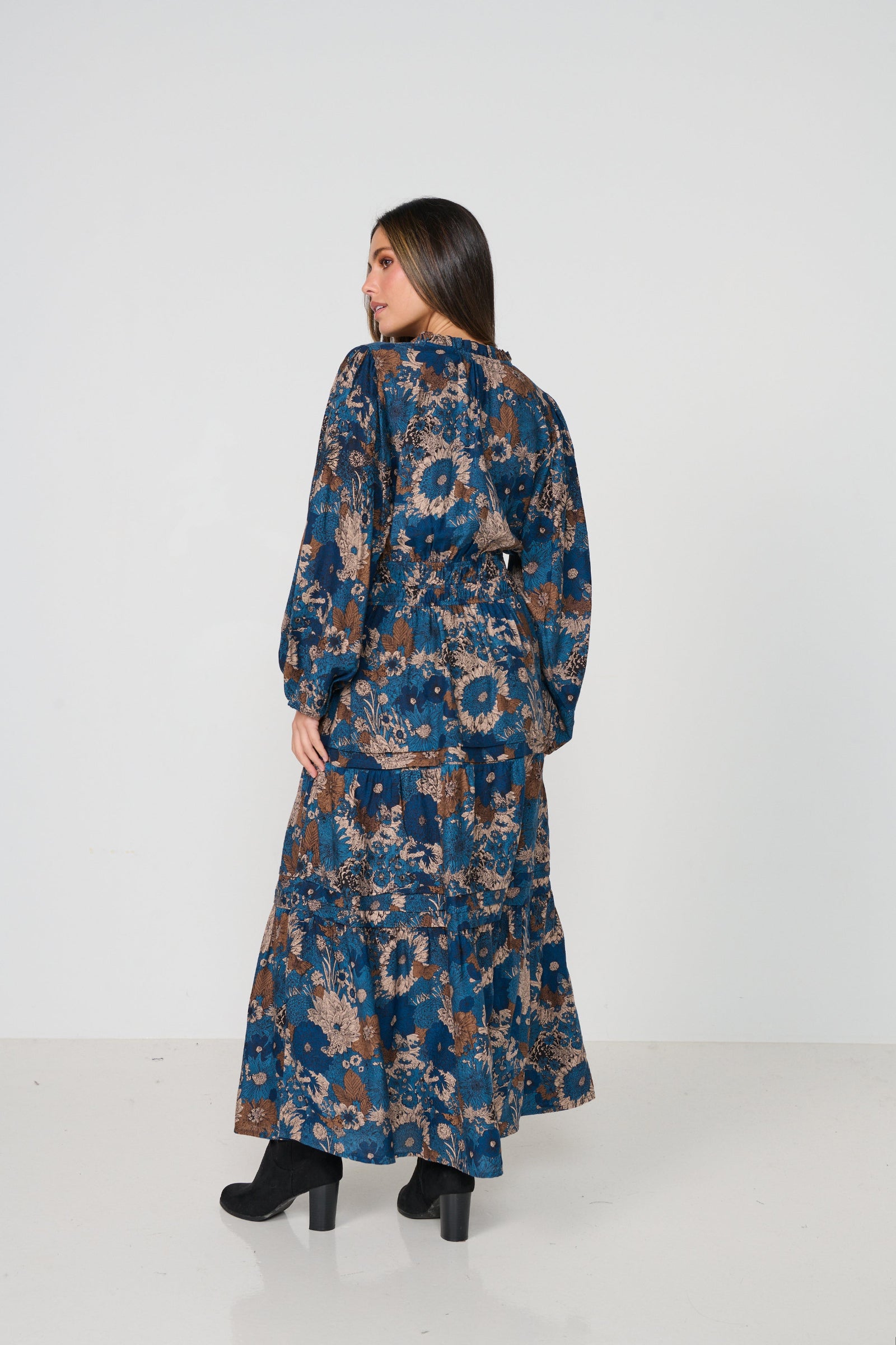 Woman wearing a long, patterned dress against a white background