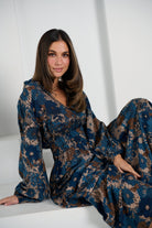 Woman wearing a blue floral dress sitting on a white surface with a white curtain background