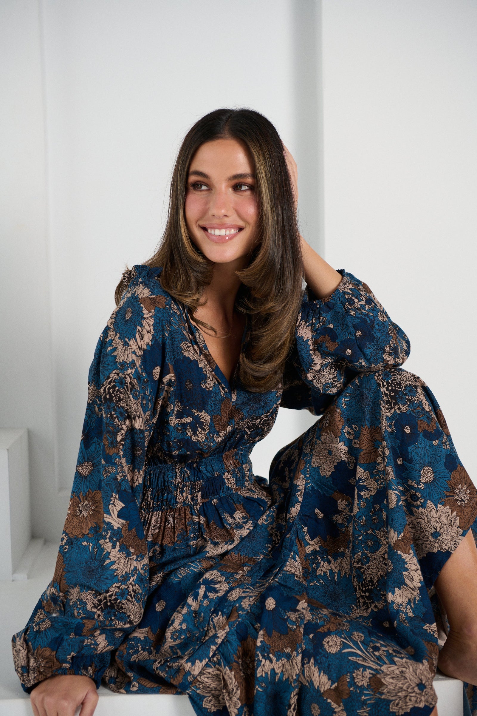 Woman wearing a blue floral dress against a white background