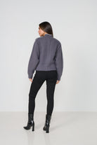 Woman wearing a cardigan and black pants on a white background