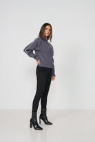 Woman wearing a gray cardigan and black pants with black boots on a white background