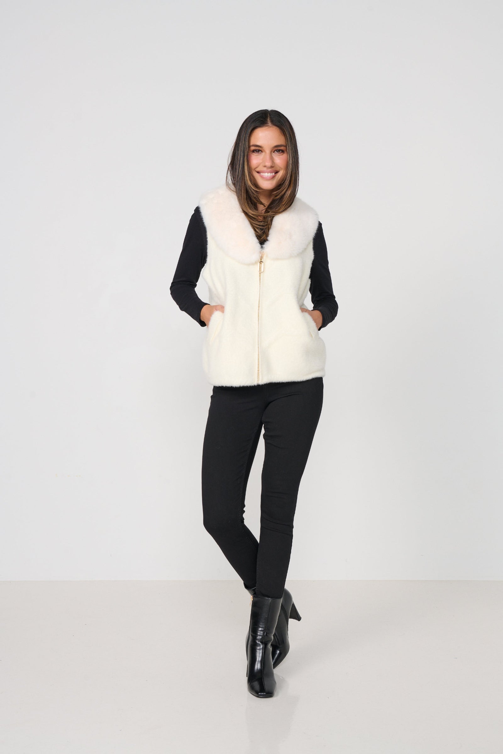 Woman wearing a white vest over a black top and pants on a white background