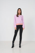 Woman wearing a pink sweater and black pants on a white background
