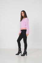 Woman wearing a pink sweater and black pants on a white background