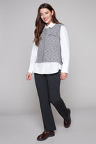 Woman wearing a white shirt, gray vest, black pants, on a gray background