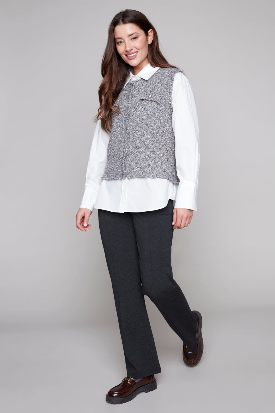 Woman wearing a white shirt, gray vest, black pants, on a gray background