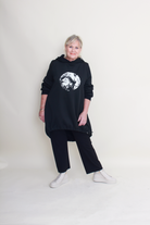 Person wearing a black hoodie with a graphic design on a plain background