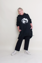 Person wearing a black outfit with a white graphic design on a plain background