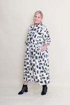 women wearing a cream dress with black and charcoal patterns on a plain background