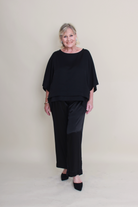 Woman wearing a black outfit against a plain background