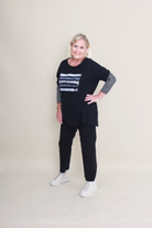 women wearing a black top with stripes and plain black pants on a plain background