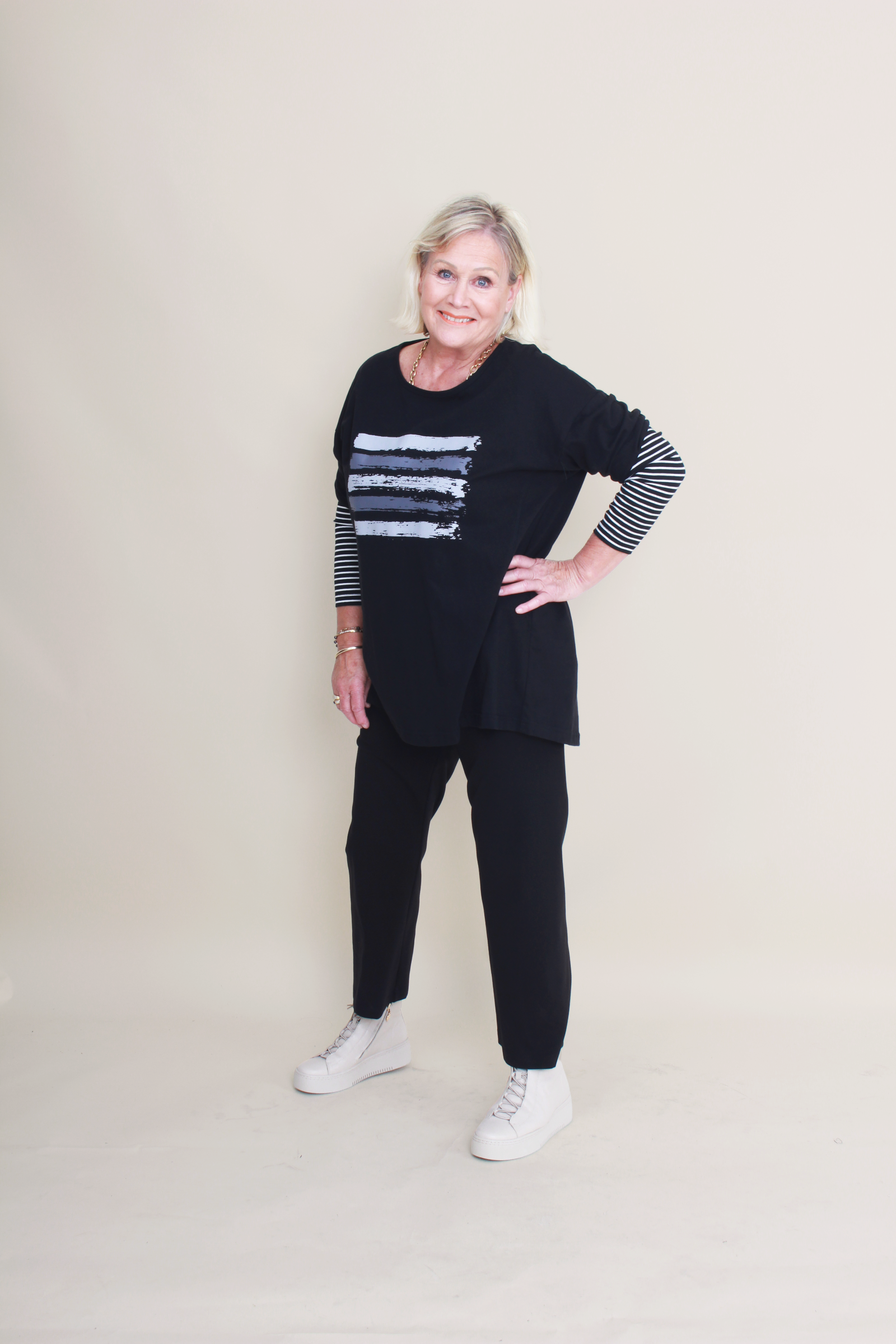 women wearing a black top with stripes and plain black pants on a plain background