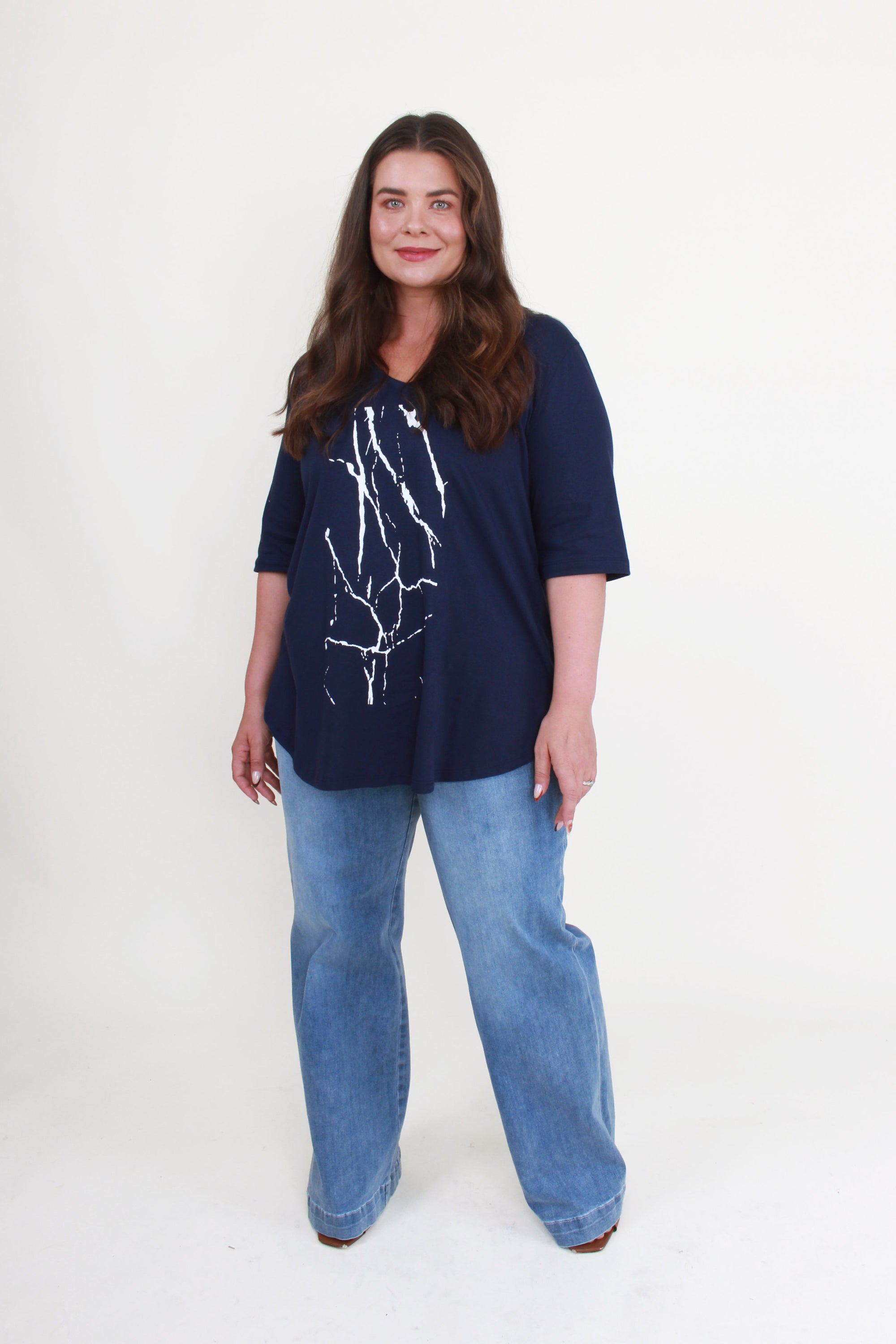 navy tee with white graphic and jeans worn by model 