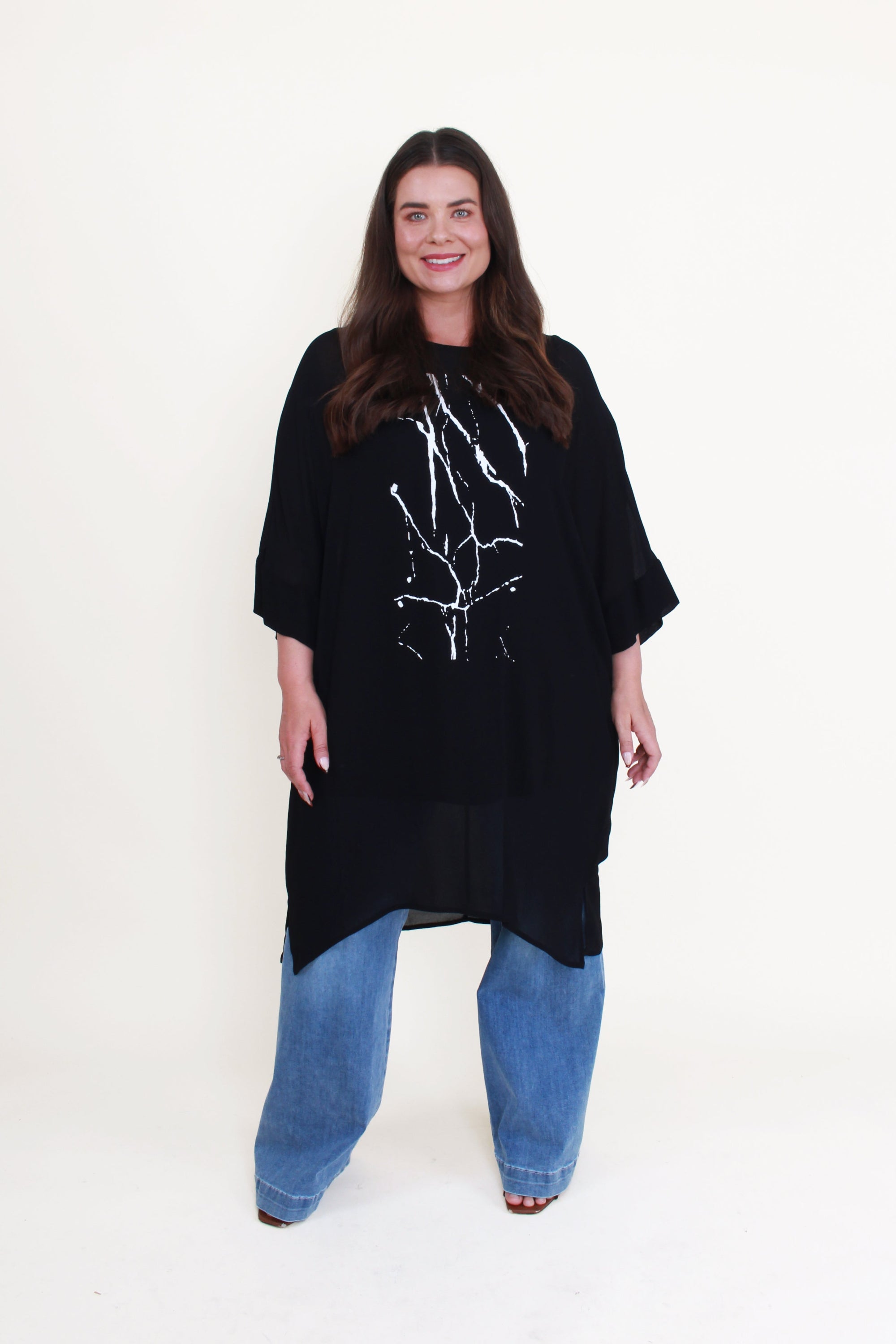 black tunic with white print and jeans worn by model 