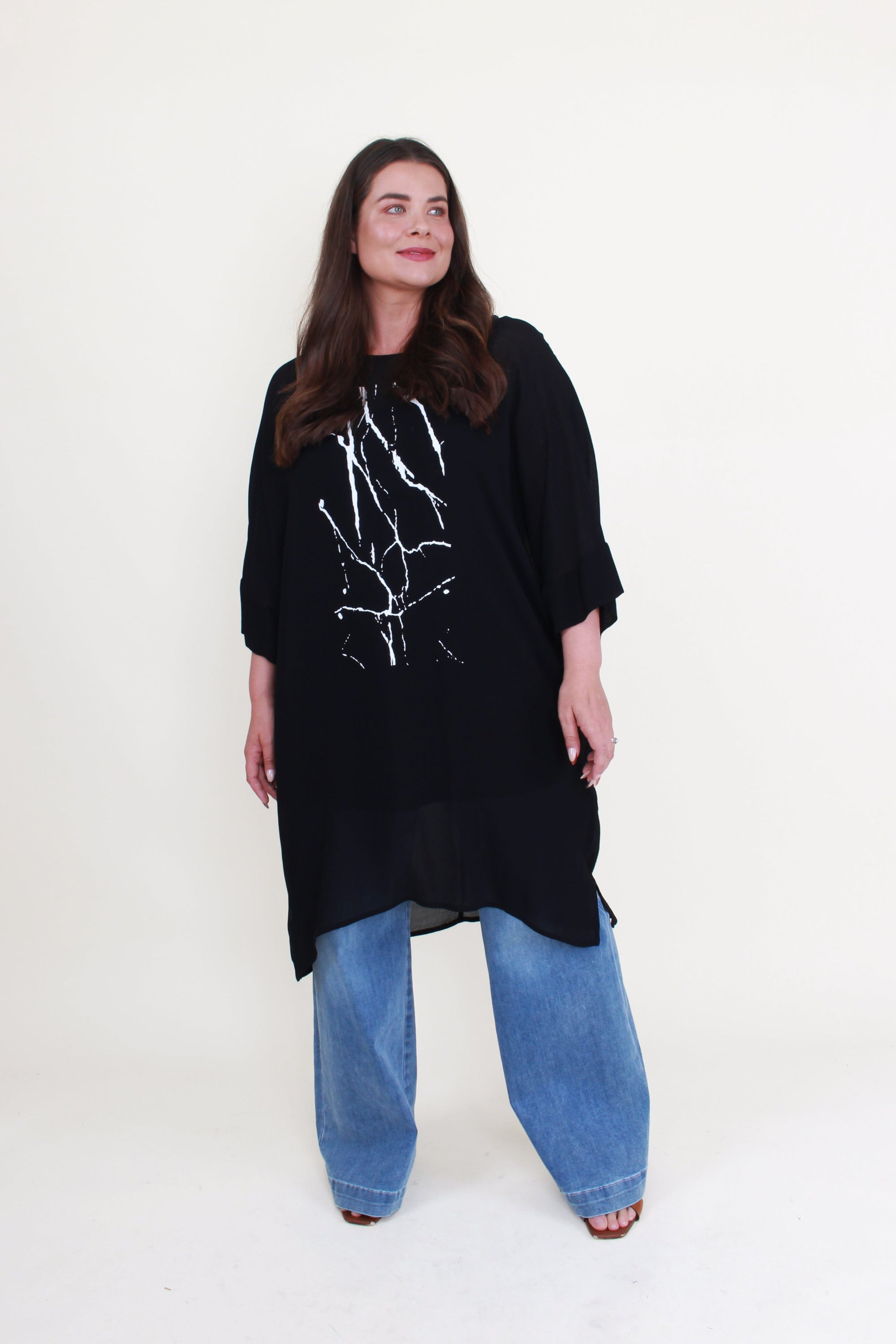 black tunic with white print and jeans worn by model 