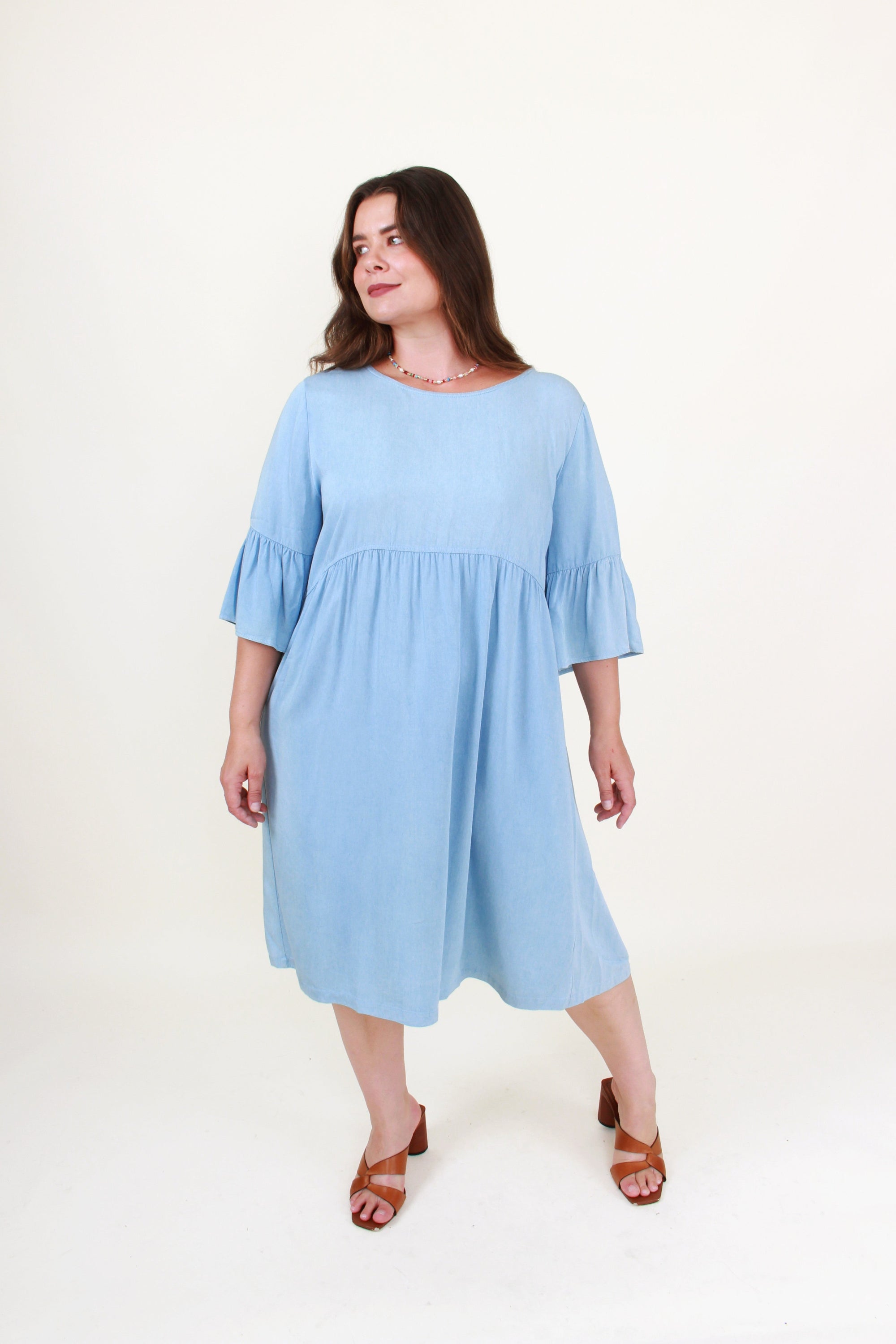 Woman wearing a light blue dress with ruffled sleeves on a white background