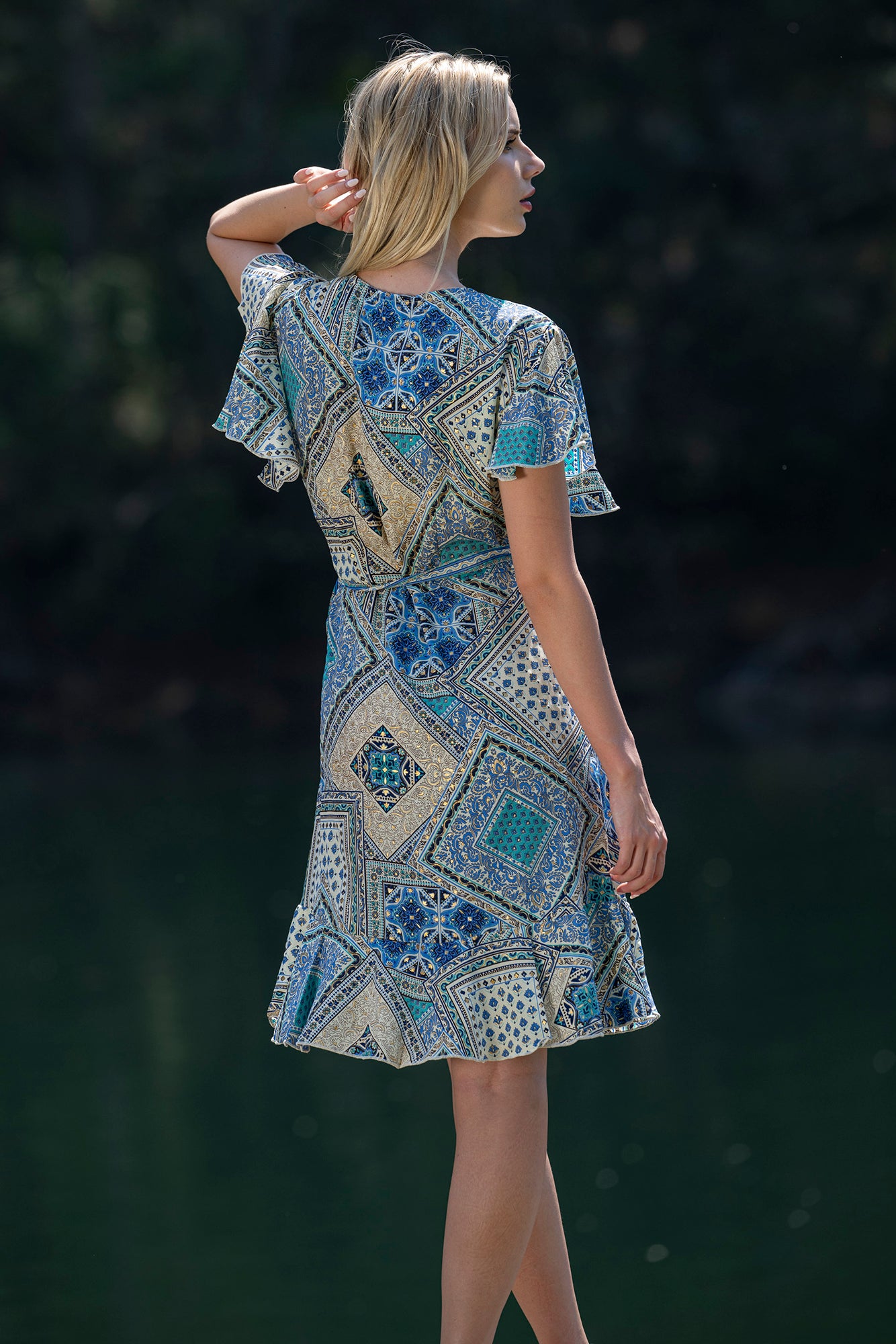 Mid length wrap dress with blue patchwork print worn by model back view