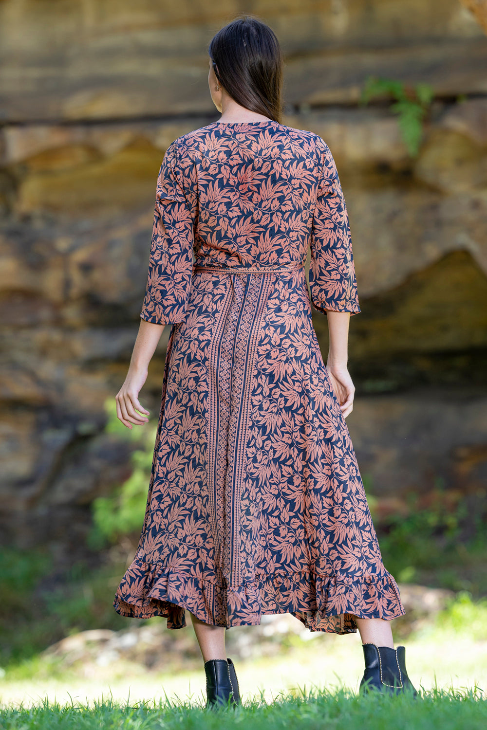 midi wrap dress in rust and navy worn by model grassy background back view