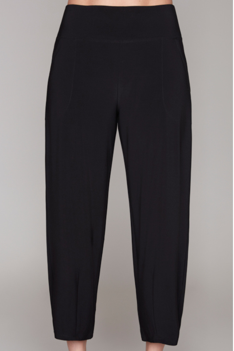 Black cropped pants with a wide waistband, modeled with black strappy high-heeled sandals against a solid gray background.