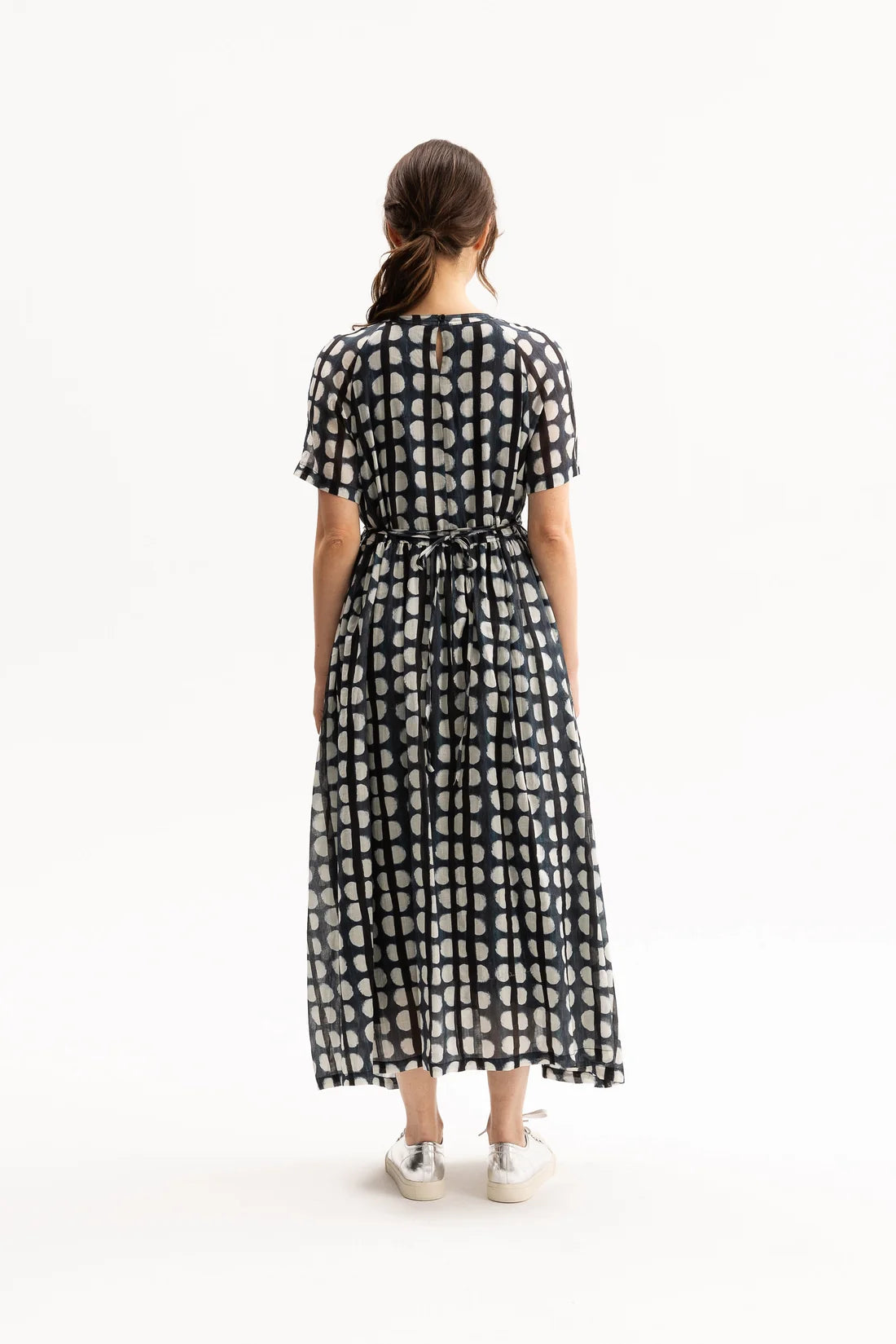 Woman wearing a black, blue, and white patterned dress on a white background