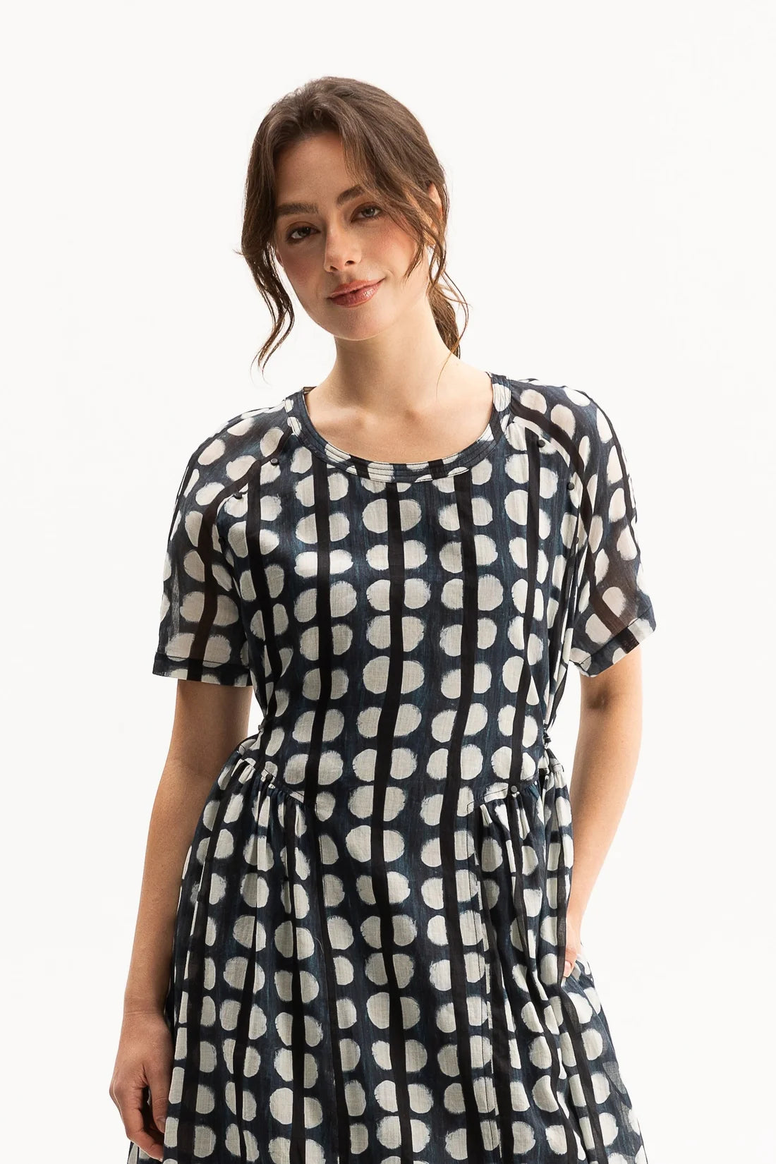 A woman wearing a short-sleeve dress with a black and white geometric pattern, standing against a plain white background.