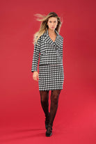 Woman wearing a black and white checkered jacket and skirt on a red background