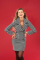 Woman wearing a black and white houndstooth pattern jacket and skirt against a red background