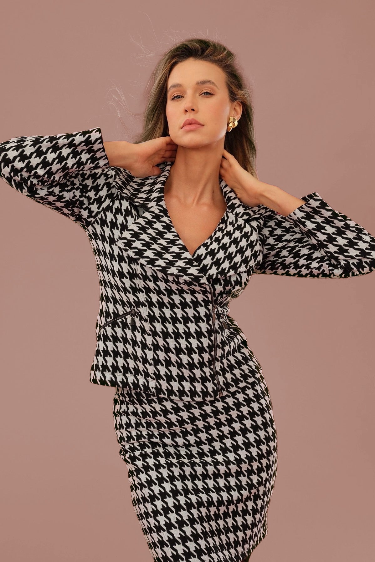 Woman wearing a black and white houndstooth patterned outfit against a brown background