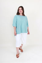 Woman wearing a light blue top and white pants on a white background