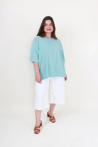 Woman wearing a light blue top and white pants on a white background