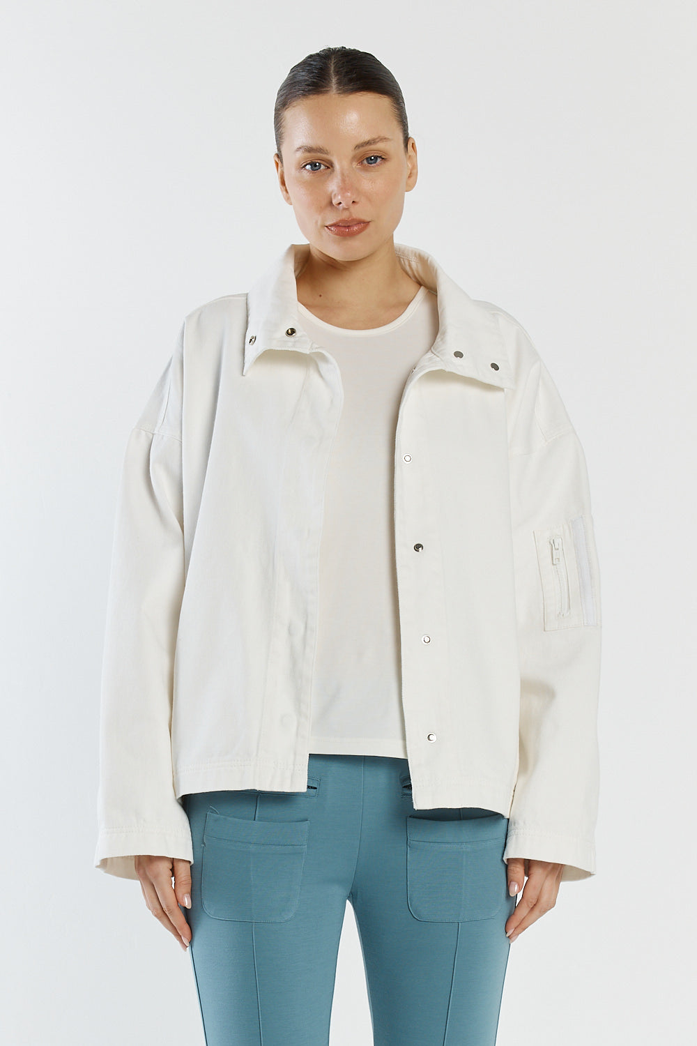 Woman wearing a white jacket over a white shirt and blue pants on a white background