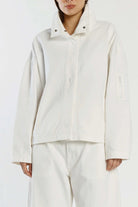 Person wearing a light-colored jacket and pants on a white background