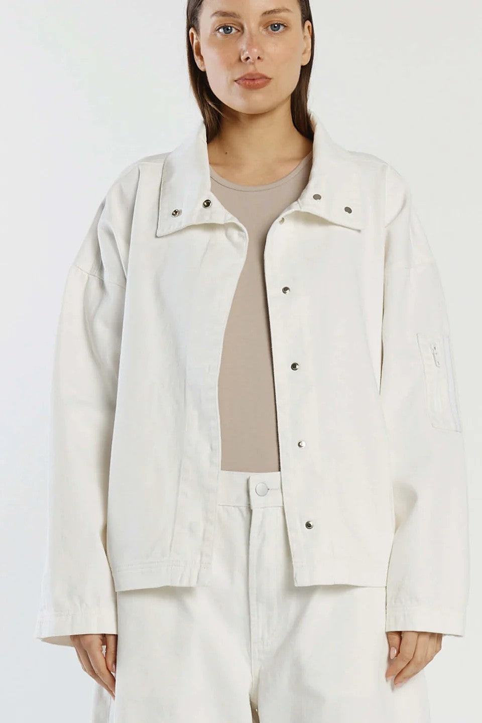 Woman wearing a white jacket and pants against a white background