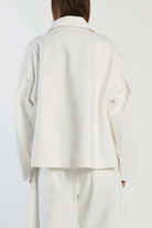 Person wearing a white coat and pants on a plain background back view