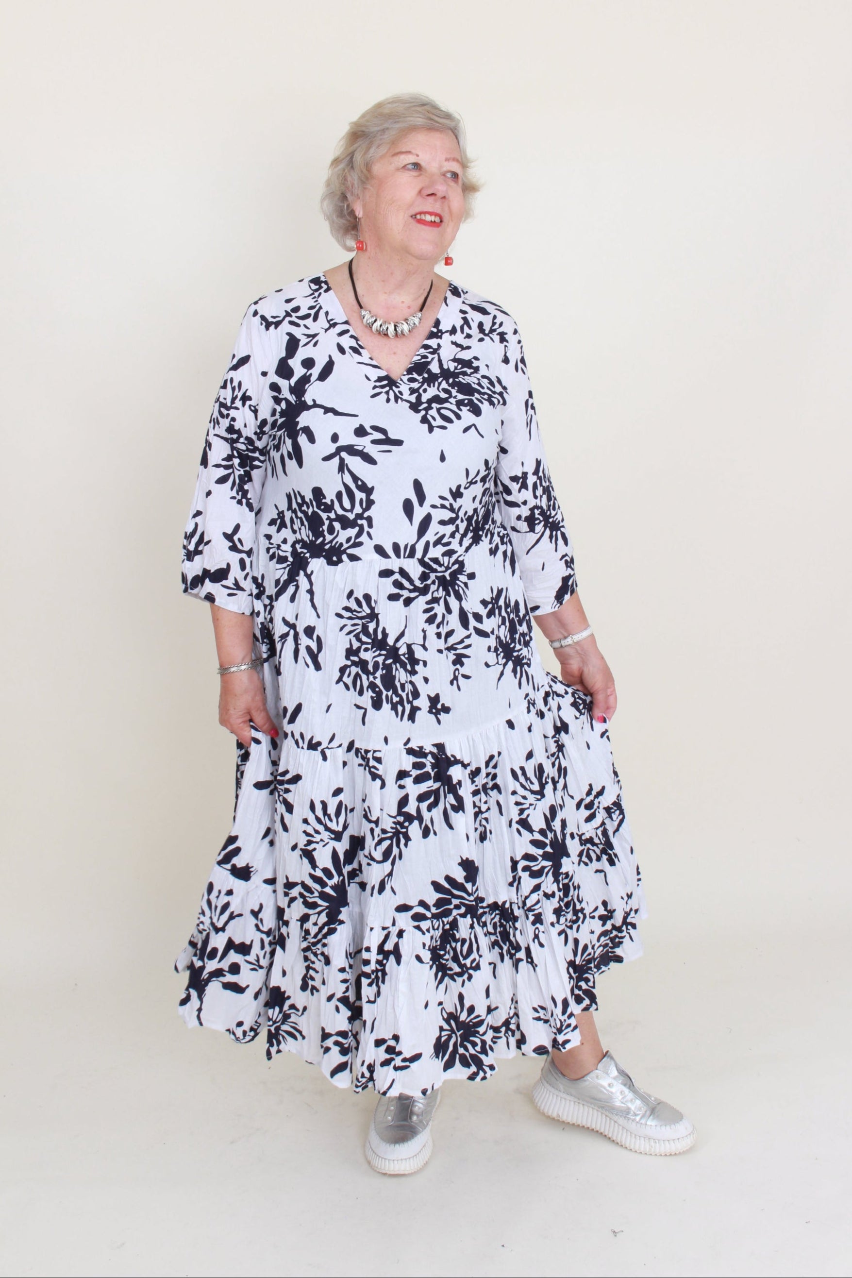 Person wearing a black and white floral dress on a plain background