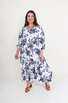 Woman wearing a white dress with black floral pattern on a white background