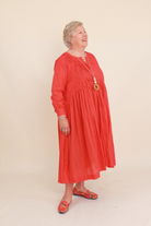 Woman wearing a red dress against a beige background