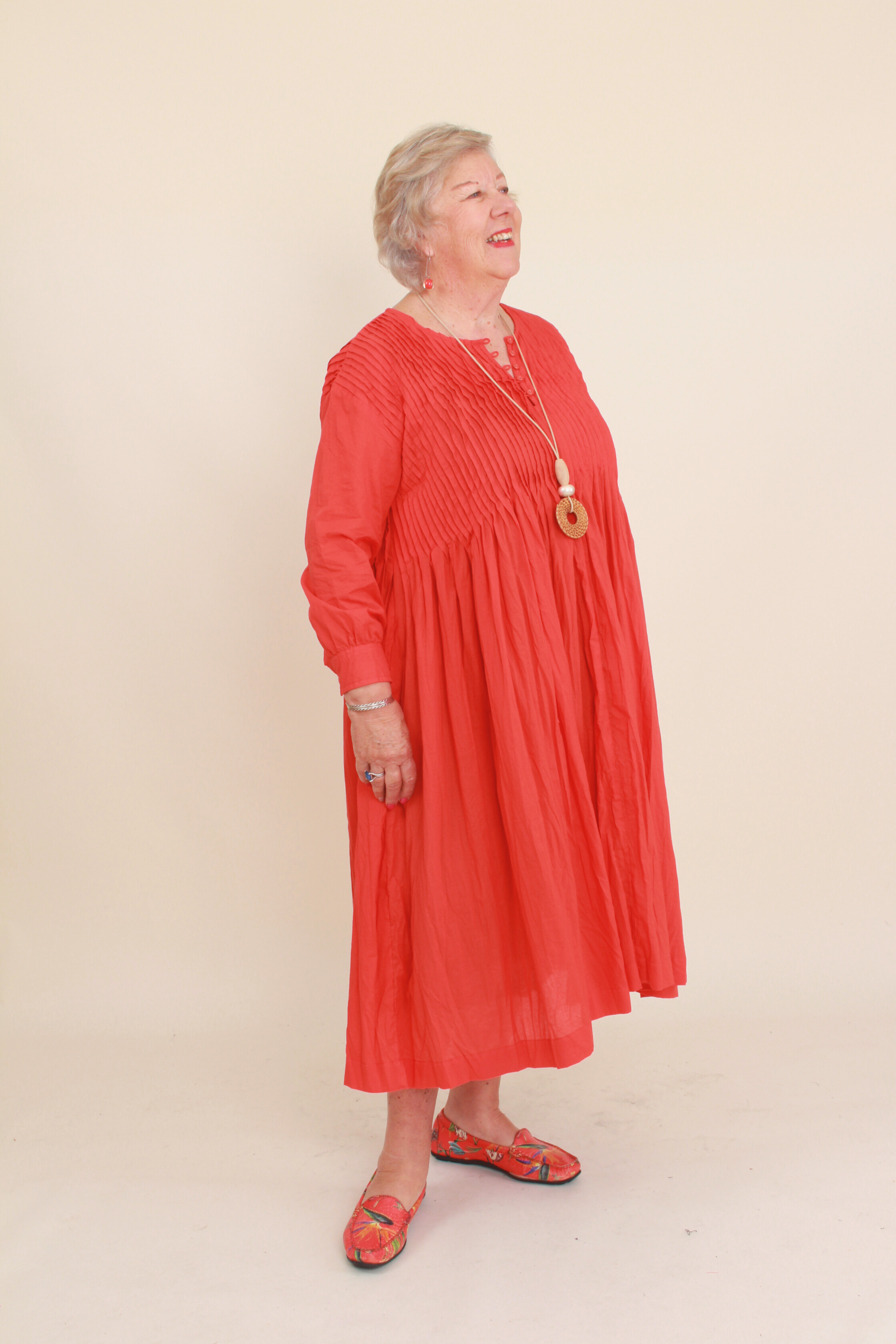 Woman wearing a red dress against a beige background