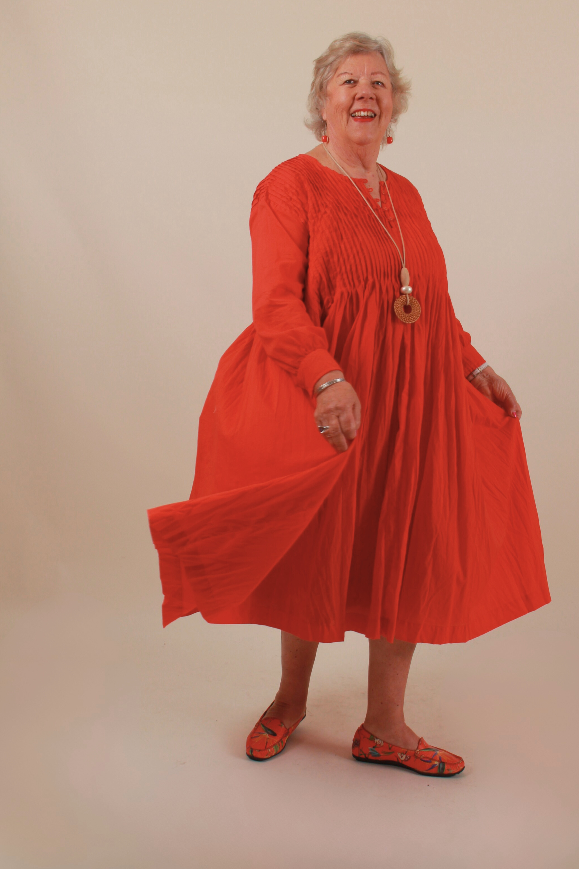 Woman wearing a red dress against a beige background