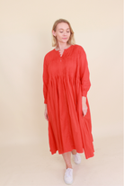 Woman wearing a red dress against a beige background