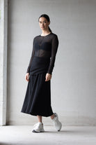 Woman wearing a black outfit with sheer panels against a plain background